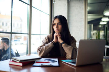 Contemplative female student with digital laptop computer thoughtful looking away while thinking about education e learning, pensive hipster girl with netbook pondering about freelance job