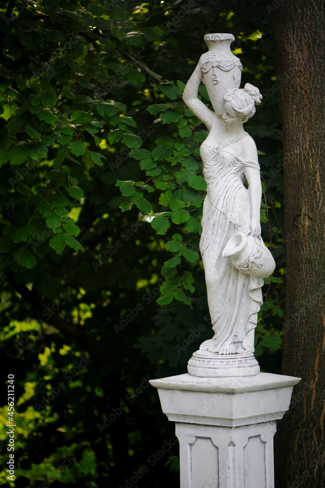 Wall mural sculpture of a girl in the spring park. an old statue in a park of a sensual semi-nude greek or ital