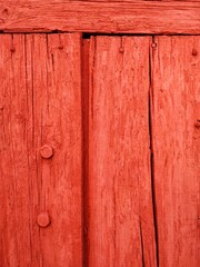 Old wooden door with pins on it, painted in red color