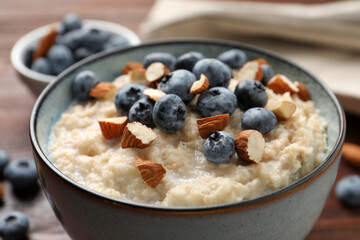 Tasty oatmeal porridge with blueberries and almond nuts on table, closeup