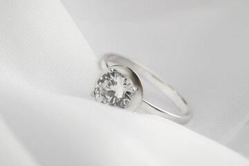 Beautiful engagement ring on white fabric, closeup