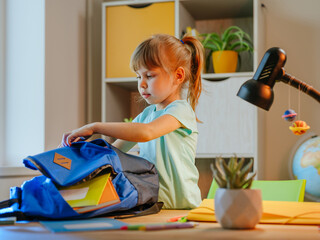 Elementary female student packing backpack for school