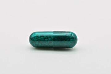 Forma farmacéutica de cápsulas verdes, aislado sobre fondo blanco