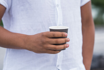 Close up of paper cup with coffee in hand of african american man