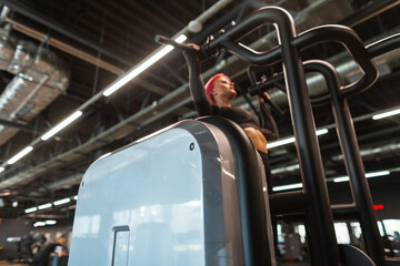 Gym focusing on the simulator against the background of a girl exercising and pulling herself up