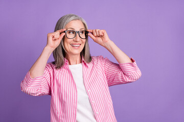 Profile side photo of aged woman happy positive smile look empty space wear eyeglasses isolated over purple color background