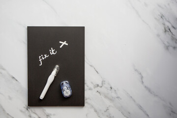 Correction tape and liquid paper on  black paper and marble background. Back to school supplies.