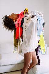 Black woman with afro hair holding pile of clothing standing in the living room