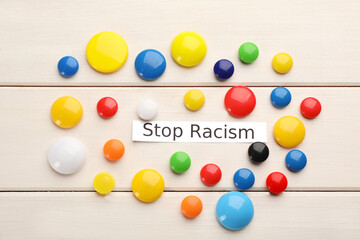 Phrase Stop Racism and colorful magnets on white wooden table, flat lay