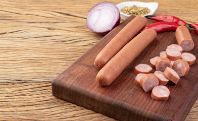 Thin pork sausage over wooden board with seasonings and copy space