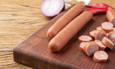 Thin pork sausage over wooden board with seasonings and copy space