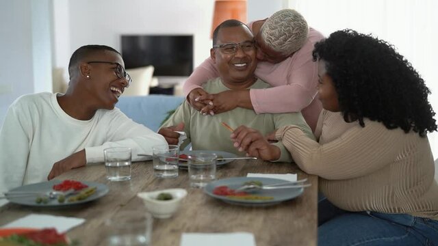 Happy African family having fun after a lunch together at home - Food and parents unity concept
