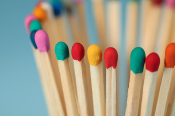 Matches with colorful heads on light blue background, closeup