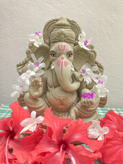 Lord Ganesh idol made of mud and decorated with white and red  flowers