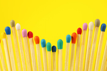 Matches with colorful heads on yellow background, closeup