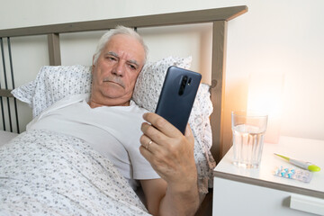 aging senior man male sick ill alone retired resting virus holding smartphone