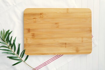 Kitchen composition, wooden cutting board mockup for engraving, towel and green branch.