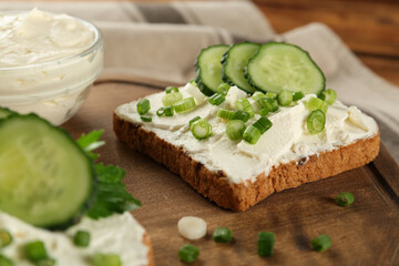 Delicious sandwiches with cream cheese, cucumber and chives on wooden board, closeup - obrazy, fototapety, plakaty
