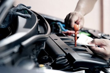 Hand a car mechanic hold the white cloth stained with engine oil checking oil level in a mechanical workshop