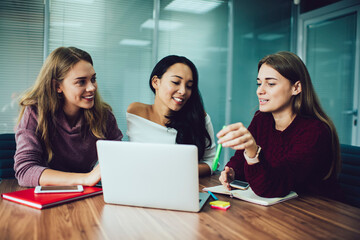 Skilled female colleagues discussing ideas for web design using netbook application during brainstorming cooperation, young executive managers with laptop computer for browsing marketing media talking