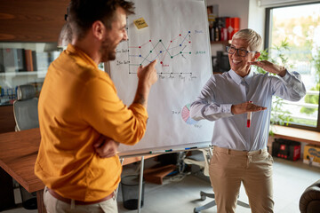 A senior business woman has a conversation with her male colleague while holding a presentation at workplace. Business, office, job