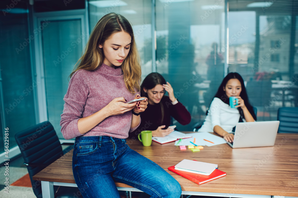 Poster caucasian woman browsing web publication via cellphone application during brainstorming meeting with