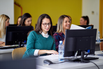Obraz premium Students in front of computers at the informatics lecture. Smart young people study at the college. Education, college, university, learning and people concept