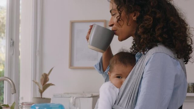 happy mother holding baby at home tired mom drinking coffee relaxing after housework washing dishes in kitchen