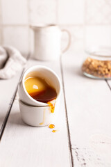 Honey is poured out of a small cup