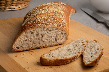 Sliced traditional sourdough loaf of bread in a special shape with seeds on a cutting board 