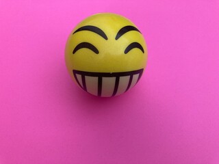 Pelota happy face amarillo sobre fondo rosa