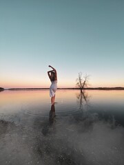 The girl stands with her back on tle lake in evening sunset