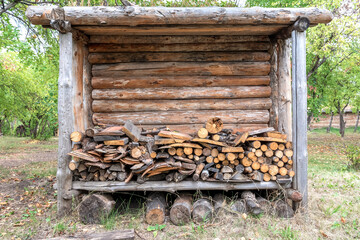 A shed with a shed for firewood stands in the garden of a village house. Rural lifestyle.