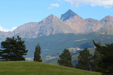 Panorama valdostano con cime d'alberi, catena montuosa e vetta del monte Emilius.