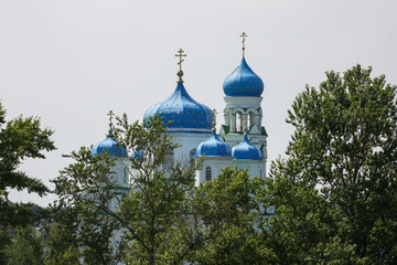 Scenic view on the christian church with blue domes and golden crosses behind the trees in Torzhok,...
