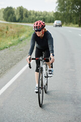 Sporty woman riding on racing bicycle while exercising on country road