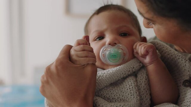 mother holding baby at home calming tired newborn gently soothing restless infant sucking on pacifier loving mom enjoying motherhood