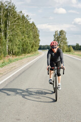 Obraz na płótnie Canvas Female athlete in helmet on road bicycle ride in beautiful nature