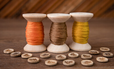 three spools of thread and buttons on a wooden table. Sewing accessories