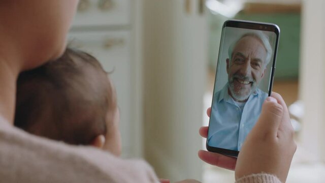 young mother and baby having video chat with grandfather using smartphone waving at grandchild enjoying family connection chatting on mobile phone