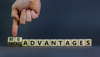 Big or small advantages symbol. Businessman turns wooden cubes, changes words Small advantages to big advantages. Beautiful grey background, copy space. Business, small or big advantages concept.