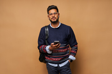 Handsome bearded indian man with backpack and mobile phone
