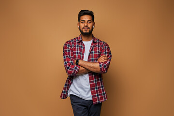 Stylish handsome indian student with crossed arms in tshirt on pastel background