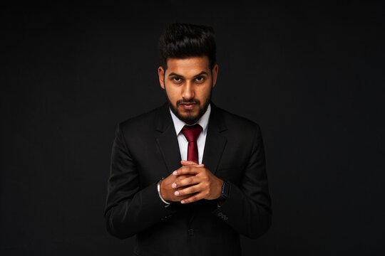 Srious indian business man in black suit on black isolated background.