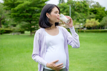 Pregnant mother sits drinking milk in a glass for good health.