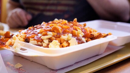 Closeup of poutine fries with gravy and cheese curds in a takeaway box