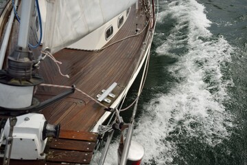 Old classic yacht sailing in an open sea during the storm. Wooden teak deck. View to the mast and...