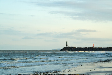 Sunny day on the beach and breakwaters in the far