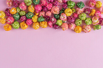 Colorful rainbow caramel candy popcorn on pink background. Cinema snack concept. Watching movie and entertainment background. Copy space for text, flat