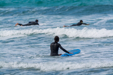 Surfers train in cold water of Atlantic ocean on famous surf Famara beach, Lanzarote, Canary...